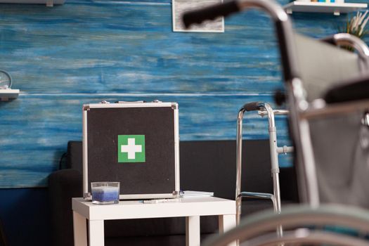 Hospital medical bag equipment standing on table in empty living room with nobody in it during healthcare therapy recovery. Social support nursing services at home. Rehabilitation assistance service