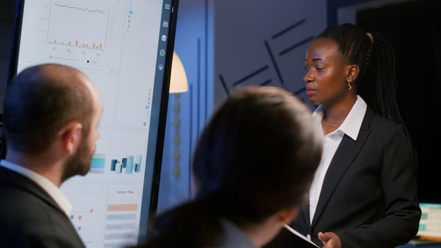 African american businesswoman brainstorming financial strategy working overtime in company meeting room late at night. Diverse multi-ethnic teamwork brainstorming management project ideas