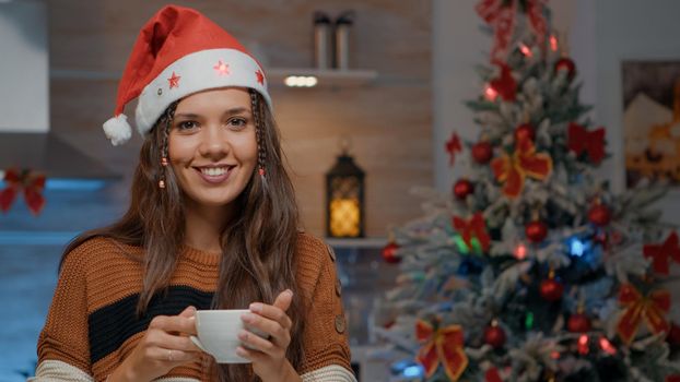 Portrait of woman pouring coffee in festive kitchen decorated for christmas celebration. Cheerful young adult smiling while preparing winter holiday beverage in december at home