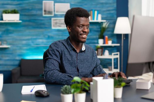 Black man computer user working from home at cozy desk, remote african american worker typing on computer, freelancer using online internet from home office. Social media browsing