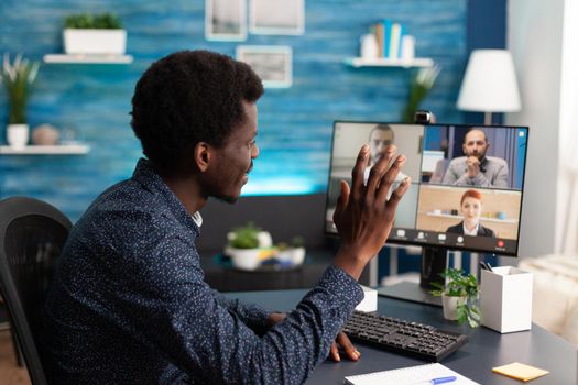 African american man on online conference video call with workmates using webcam communication. Remote internet worker working from home keeping distance while using technology