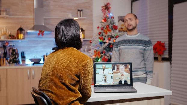 Woman using video call for work meeting on christmas eve while frustrated man waiting to celebrate holiday festivity. Person working on business instead of enjoying seasonal celebration