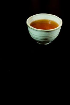 Tea in ceramic cup on black background