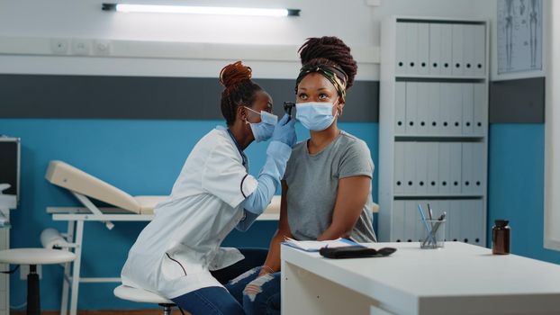 Doctor consulting patient with otoscope for ear examination at annual checkup visit. Otologist doing consultation with medical tool, checking for infection and diagnosis on woman.