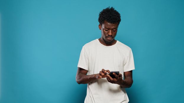 Confused man using smartphone for text messages and browsing internet. Portrait of modern person looking at mobile phone with touch screen for online communication feeling disoriented.