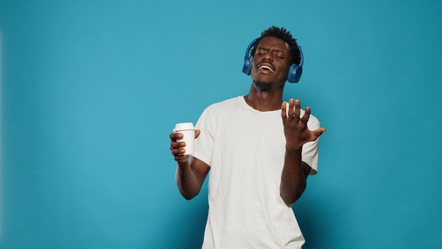 African american man using headphones to listen to music in studio. Black person with headset dancing to audio for entertainment. Afro adult listening to song rhythm while having fun