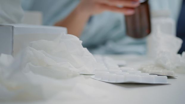 Close up of hand of sick woman searching for pills and capsules on table. Person looking for illness treatment and medicaments against coronavirus infection. Adult with headache and flu