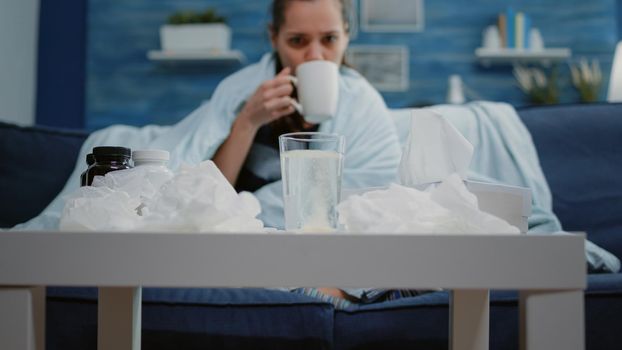 Close up of woman putting effervescent pill in glass of water preparing medication treatment against seasonal flu. Sick adult with cold having beverage with vitamin to cure virus symptoms.