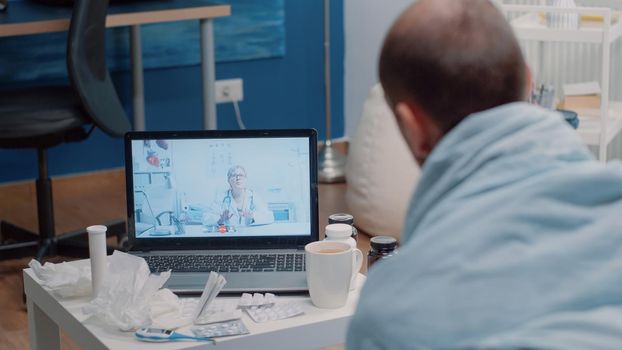 Sick man using video call telemedicine for consultation, asking about cold and flu symptoms and treatment against disease. Patient talking to medic on online remote conference to cure pain