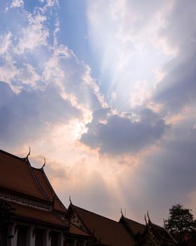 Sun beam behind the sunset clouds over the buddhist temple