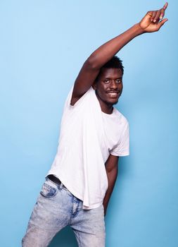 Carefree adult dancing and smiling while looking at camera. Portrait of person doing dance moves for enjoyment while posing over isolated background. Positive man feeling happy