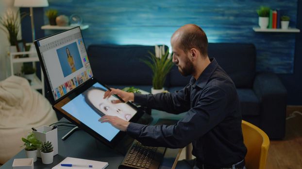 Male photographer doing editing work on touch screen monitor at studio. Photography editor working on retouching software and graphic tablet with stylus for professional pictures