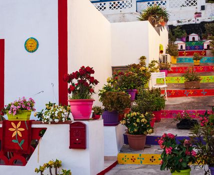 View of a typical colored house in Linosa with the staircase full of flower pots