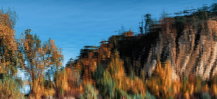 Abstract natural background. Reflection of an autumn forest in the water of a mountain lake