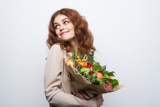 portrait of a woman fun posing fruit bouquet vitamins light background. High quality photo