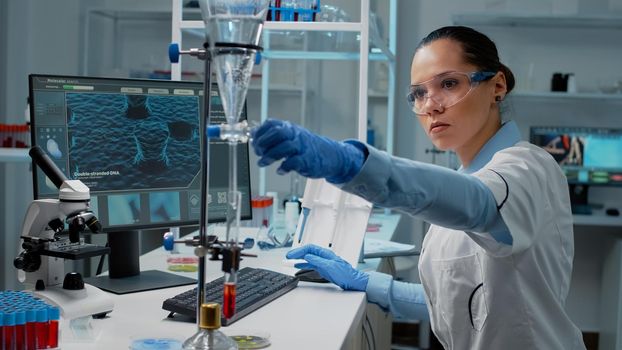 Portrait of doctor using chemical glassware on desk in laboratory for analysis. Biochemistry scientist with blood in test tube and dripping pipe for scientific healthcare development