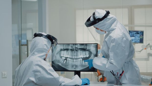 Professional stomatologist looking at teeth animation on screen and comparing model for patient dentition at clinic. Dental assistant using virtual computer technology for operation