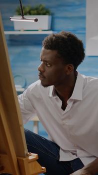 Artist of african american ethnicity working on drawing of vase at art studio. Black young adult using pencil and canvas on easel for creative masterpiece. Person with fine art project