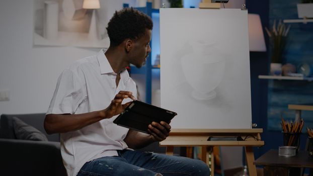 Young african american artist using digital tablet for art drawing project at studio. Black man with creativity skill holding device for modern masterpiece and professional fine art