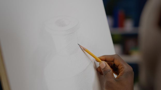 Close up of white canvas with vase drawing and black hand holding pencil for authentic design at studio. African american artist using art tools and instruments for innovative masterpiece