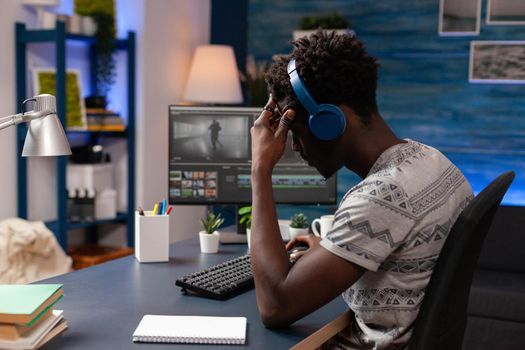 African american videomaker retouching film footage using editing post production sofware working at visual effects for multimedia project. Young videographer sitting at desk looking at movie