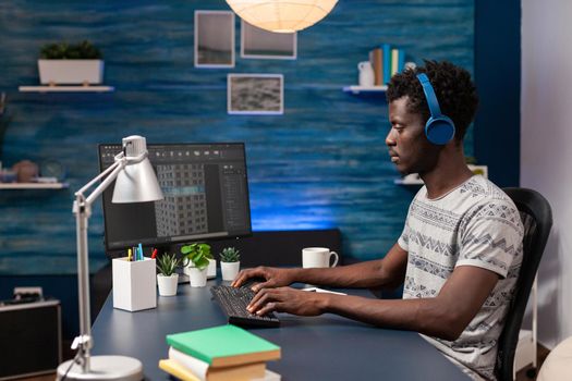 African american engineer designer with headset analyzing architecture sketch on computer developing building construction plan. Young architect working remote from home at skyscraper concept project