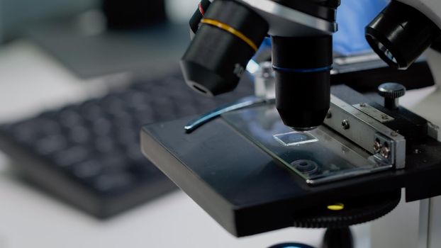 Close up of glass tray on microscope for examination in laboratory. Chemical instrument used for dna research and analyzing bacteria. Doctor hands fixing sample tool for optical investigation