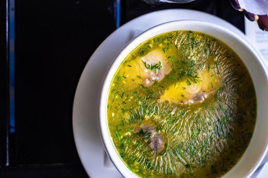 Traditional fish soup served in the white ceramic bowl on the table