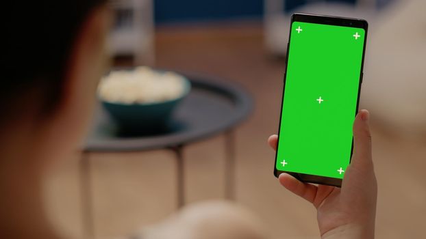 Close up on mobile phone with vertical green screen used for modern technology and blank copy space with mockup template. Woman holding device with isolated background and chroma key