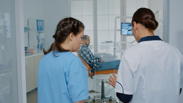 Dentistry team discussing procedure using x ray on tablet before oral care consultation at clinic. Stomatologist in dental cabinet doing professional examination of patient teethcare