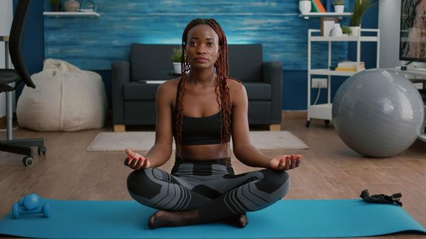 Flexible flexible athlete woman relaxing in lotus position on floor in living room enjoying healthy lifestyles. Fitness woman in sportwear streching muscle during morning gymnastics