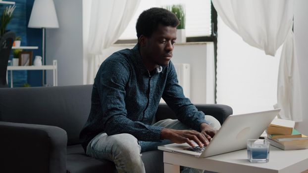 Working from home black man in flat apartment, happy african american remote worker using laptop computer, male workplace for online internet business, using social media