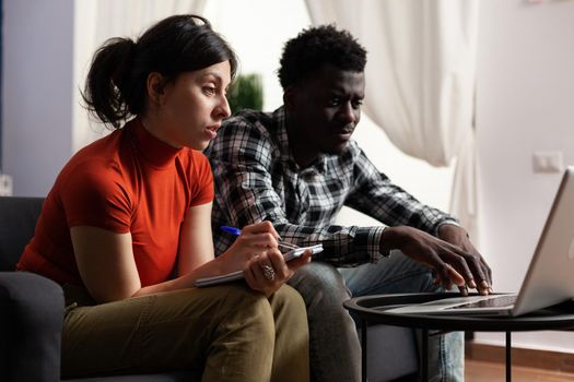 Interracial couple calculating tax money using laptop for economy and budget. Married multi ethnic lovers with notebook doing taxes and financial accounting, checking online payment