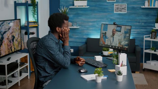 Black man with toothache seeking medical stomatologist health advice via internet video call communication. Online telehealth diagnose using webcam teethcare consultation, dental hygiene and orthodontist advice