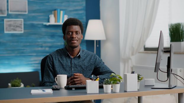 Portrait of charming handsome african american man smiling to camera, young black man in cozy modern flat apartment. Happy succesful attractive freelancer of african ethnicity. Slow motion shot