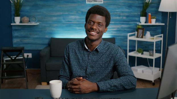 Portrait of handsome african american man looking into camera, smiling young black man in cozy modern flat apartment. Happy succesful attractive freelancer of african ethnicity. Slow motion shot