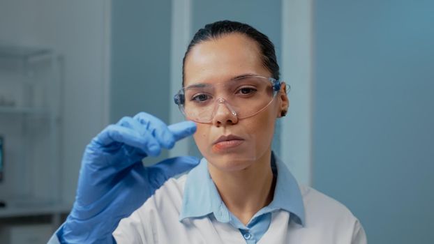 Portrait of doctor in laboratory analyzing blood sample on glass. Scientific woman holding dna plasma for healthcare examination and research. Scientist with chemical lab equipment