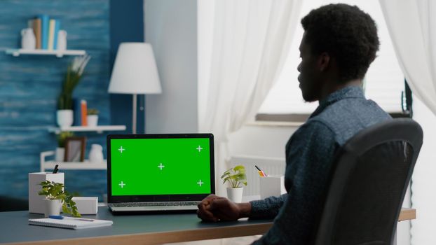 African american man looking at green screen isolated mock up laptop display in bright flat. Freelancer computer user using isolated mockup computer