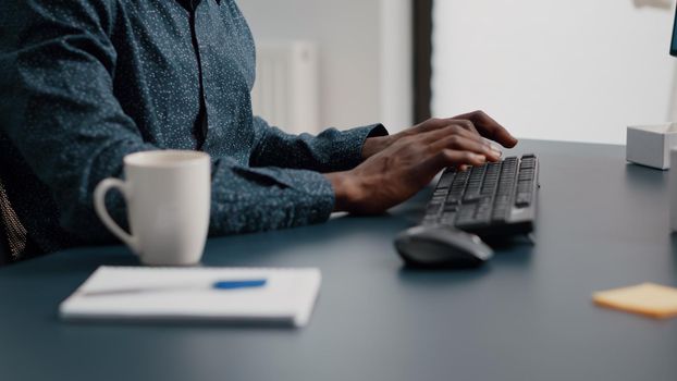 Black african american manager working from home, tuping on computer keyboard. Panning close up shot from hands to the face. Bright nice home office