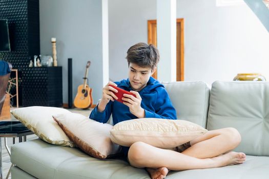 The boy playing online game on smartphone at home.