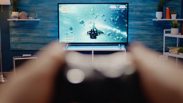 Close up of gaming TV in modern living room at home. POV of video games on television. Excited person hands playing with controller using console as entertainment activity and fun