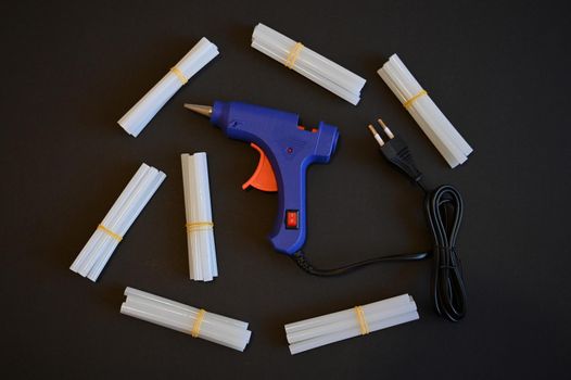 glue gun with glue rods lies on a black background isolate close-up