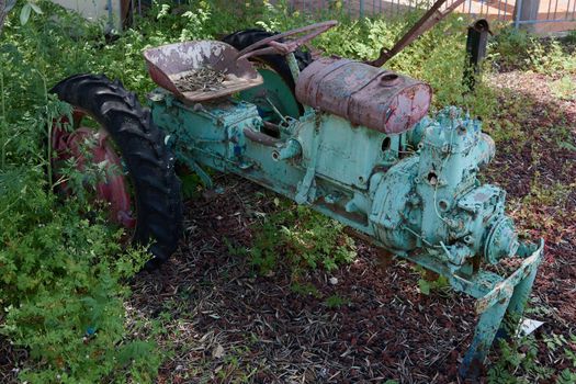 an old tractor skeleton with peeling paint in different colors many layers of pink and light green shades