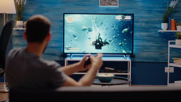 Young man winning action video games playing with controller at home. Person using console with joystick for virtual cheerful activity on television for modern entertainment and fun