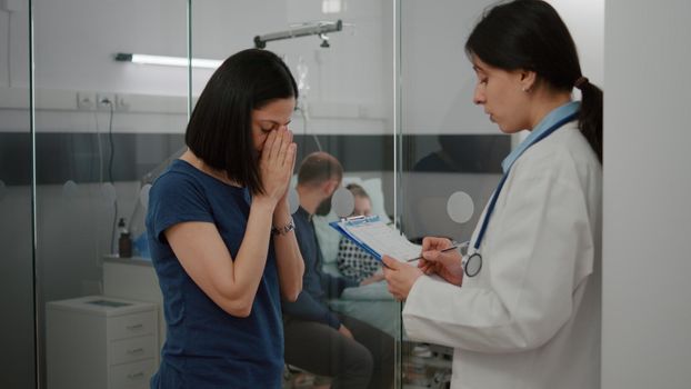 Practitioner doctor explaining sickness diagnosis to panicated worried mother discussing disease treatment during medical examination in hospital ward. Hospitalized sick girl recovering after surgery