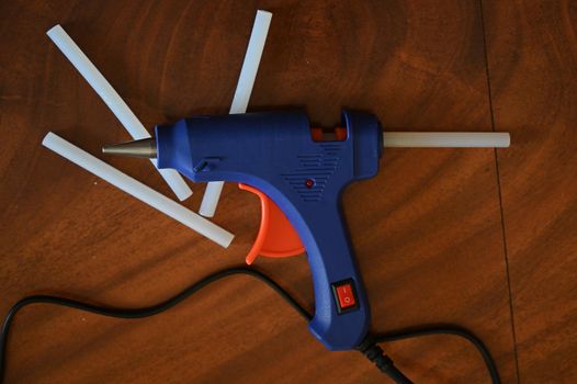 a glue gun with glue rods is lying on the table close-up