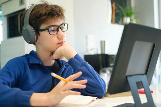 Distance learning online education. A schoolboy boy studies at home and does school homework. A home distance learning.