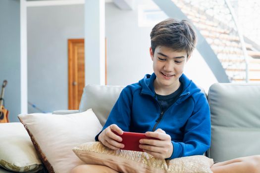 The boy playing online game on smartphone at home.