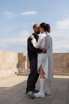 Happy married couple celebrating relationship anniversary standing on tower rooftop enjoying looking at metropolitan city panoramic view from observation point. Landscape of urban building