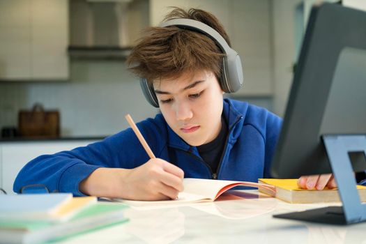 Distance learning online education. A schoolboy boy studies at home and does school homework. A home distance learning.